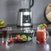 A blender is shown in the background, with ingredients and a finished drink in the foreground. Voir les images du produit