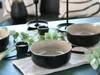A table setting with bowls, small cups, and greenery. Produktbild-Vorschau