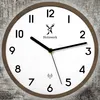 A close-up view of a modern wall clock with a wooden frame, set against a textured background. Voir les images du produit