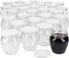 A collection of empty glass jars with white lids, and one jar filled with dark red jam or preserves. Produktbild-Vorschau