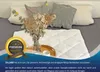 A white quilted blanket is laid out on a bed with pillows and a vase of dried flowers. Produktbild-Vorschau