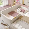A modern children's bed with a light-colored frame and pink accents, featuring pillows and a blanket. A window with sheer curtains is visible in the background. Podgląd zdjęcia produktu