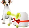 A dog sits next to an automatic ball launcher with a tennis ball being launched. Voir les images du produit
