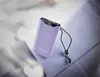 A purple power bank with a digital display showing '90%' is placed on a textured surface, with a black lanyard attached. Voir les images du produit