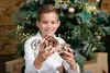 A young boy is holding a wooden model motorcycle in front of a decorated Christmas tree. Anteprima dell’immagine prodotto