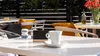 An outdoor cafe table setting with a cup of coffee, salt and pepper shakers, and a small chalkboard sign. Anteprima dell’immagine prodotto
