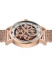 A close-up, studio shot of a skeletonized automatic watch with a rose gold case and mesh bracelet, set against a white background. Náhled obrázku produktu