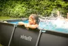 Children playing in a rectangular swimming pool in a garden. Produktbild-Vorschau