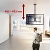 A person walks through a modern, well-lit interior space, possibly an airport or office building, with a TV mounted on a ceiling bracket. Anteprima dell’immagine prodotto