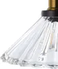 A close-up view of a glass lampshade with a ribbed texture, attached to a black and brass fixture. Náhled obrázku produktu