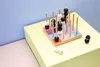 A wooden board game with black and white beads on wooden pegs, placed on a yellow surface with a blue and pink background. Produktbild-Vorschau