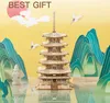A 3D wooden pagoda model is displayed with decorative mountains and cranes against a yellow background, suggesting it's a gift. Voir les images du produit