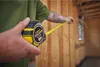 A person is using a Stanley FatMax tape measure to measure a wooden structure. Voir les images du produit