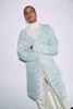 A woman wearing a white turtleneck and a long, patterned cardigan stands against a white background. Produktbild-Vorschau