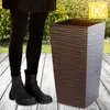 A person standing next to a tall planter on a wooden deck with greenery in the background. Anteprima dell’immagine prodotto