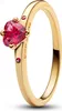 A close-up studio shot of a gold ring with a heart-shaped red gemstone. Produktbild-Vorschau