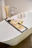 A bathtub caddy with a book, candle, and wine glass on it. Podgląd zdjęcia produktu