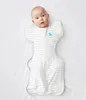 A baby is swaddled in a white and gray striped swaddle sack on a white background. Produktbild-Vorschau