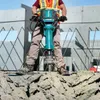 A person is using a jackhammer to break up concrete on a construction site. Anteprima dell’immagine prodotto
