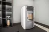 A pellet stove is shown in a room next to a shelf unit. Náhľad obrázku produktu