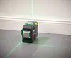 A laser level tool is placed on a tiled floor, projecting green laser lines onto the wall and floor. Produktbild-Vorschau