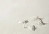 Several white rocks are arranged on a textured white surface, resembling a zen garden. Produktbild-Vorschau