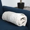 A rolled-up blanket is placed on a blue sofa. Produktbild-Vorschau