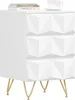 A white nightstand with a geometric drawer front design and gold legs, shown from a 3/4 angle. Books and a cup are on top. Produktbild-Vorschau