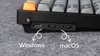A close-up view of the side of a black mechanical keyboard, showing the USB-C port and two toggle switches. Arrows point to the switches, with text labels 'Windows' and 'macOS' indicating their function. Produktbild-Vorschau