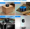 A collage of four images showing a small, round speaker being used in different environments: on a cardboard box, on a wooden desk, on a car dashboard, and attached to a glass panel. Náhled obrázku produktu