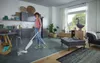A woman is using a steam mop in a modern living room and kitchen area. Anteprima dell’immagine prodotto
