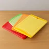 Four colorful cutting boards are arranged diagonally on a wooden surface. Produktbild-Vorschau