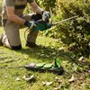 A person is using an electric hedge trimmer in a garden, with a power strip on the grass. Produktbild-Vorschau
