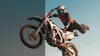 A split image showing a motocross rider performing a jump. The left side is blurred and shows a motorcycle wheel in motion, while the right side shows a clear image of the rider and motorcycle in mid-air. Produktbild-Vorschau