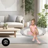 A young girl in a ballet outfit sits on a round swing in a living room setting. Produktbild-Vorschau