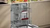 An open dishwasher with two racks filled with dishes, set in a kitchen environment. Produktbild-Vorschau