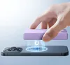 A hand is holding a purple portable charger above a black smartphone, demonstrating magnetic charging. Podgląd zdjęcia produktu