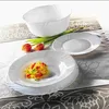 A white serving bowl and two white plates are arranged on a patterned tablecloth. One plate contains pasta with tomatoes and basil. Two tulips are placed behind the plate with pasta. Voir les images du produit