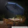 An outdoor patio scene at dusk with a table, chairs, and a large navy blue umbrella with LED lights. Produktbild-Vorschau