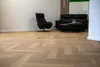 A living room with wooden flooring, a black recliner chair, and a black sofa with a coffee table. Produktbild-Vorschau