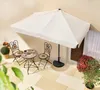 A patio set with a table, two chairs, and an umbrella on a tiled patio. Produktbild-Vorschau