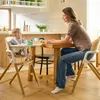 A mother and baby are sitting at a wooden table in a kitchen. The baby is in a high chair and the mother is looking at the baby. Voir les images du produit