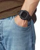 A person wearing a black digital watch on their wrist, with their hand in their blue jeans pocket. Náhľad obrázku produktu