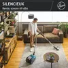 A man is vacuuming a living room with a Hoover vacuum cleaner. Produktbild-Vorschau