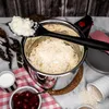 A close-up overhead shot of a pot of cooked rice with a spoon lifting some out, surrounded by ingredients like cherries and milk, and uncooked rice. Náhled obrázku produktu