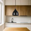 A black pendant lamp hangs in a modern kitchen setting. Náhled obrázku produktu