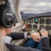 A person flying a small airplane, wearing headphones and a smartwatch. Voir les images du produit