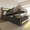 A modern upholstered bed frame with the mattress lifted to reveal storage space underneath. The bed has integrated LED lighting. Voir les images du produit