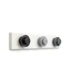 A white wall with a white shelf holding three LEGO brick-shaped coat hooks in black, light gray, and dark gray. Anteprima dell’immagine prodotto