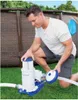 A man is shown kneeling next to a pool filter pump, appearing to be setting it up or performing maintenance. Voir les images du produit